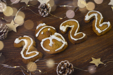 Flatlay in dark colors. Ginger Cookie Snowman, numbers 2022 are made by children from ginger cookies.Bokeh lights garlands and golden decorations