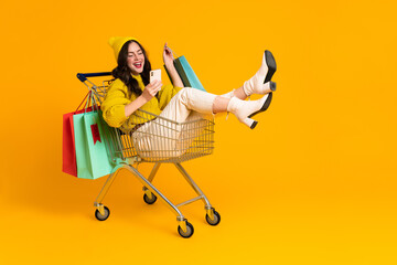 White excited woman laughing and using cellphone in shopping cart