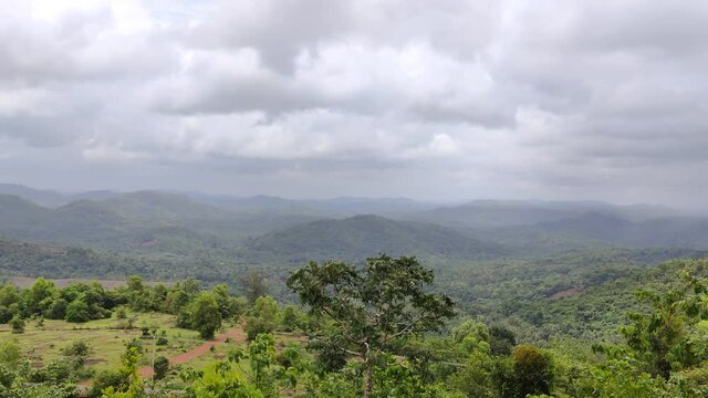 distant view of hills and valleys under the cloudy sky with greens in a Kerala tourist destination