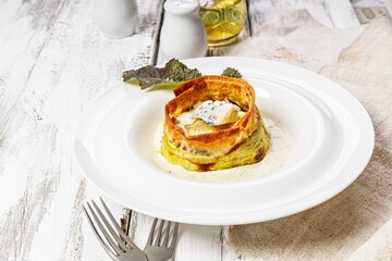Close-up delicious vegetarian muffin with zucchini and blue cheese. Cheese sauce and mustard leaves. Tasty and healthy food. Restaurant serving and dish decoration on a white plate. Copy space
