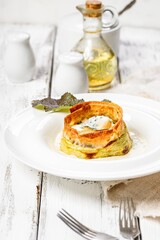 Delicious vegetarian muffin with zucchini and blue cheese. Cheese sauce and mustard leaves. Tasty and healthy food. Restaurant serving and dish decoration on a white plate. Vertical food still life