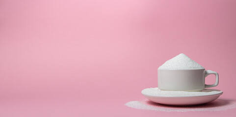 White cup overflowing with sugar on a pink background. Excessive sugar intake. There is a place for...