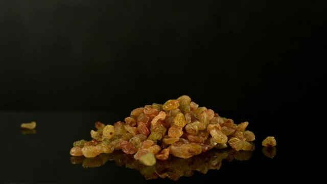 golden raisins falling on the table, close-up, slow motion video