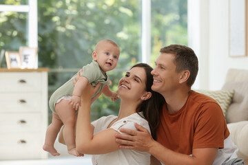 Fototapeta premium Portrait of happy family with their cute baby at home