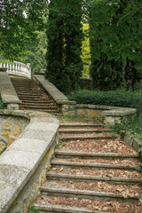 old stone staircase in an abandoned park. Fallen leaves lie on old steps and railings of stairs. concept is abandoned architecture of city.