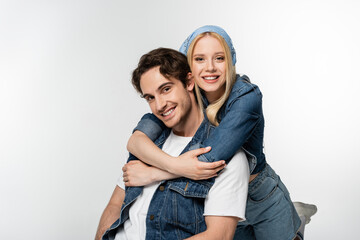 cheerful couple in denim clothes embracing while smiling at camera isolated on white