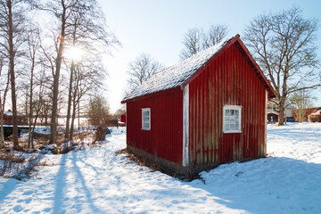 Swedish winter landscape with lots of snow and blue sky and traditional red and white houses in a rural scene