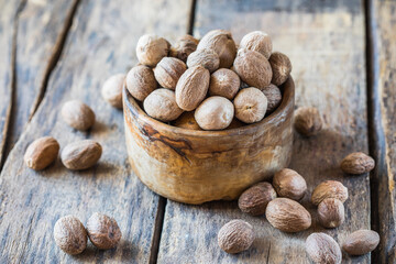 Ground nutmeg in  bowl and whole nuts on an old wooden background