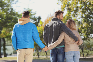Obraz premium Woman holding hands with another man behind her boyfriend's back during walk in park. Love triangle