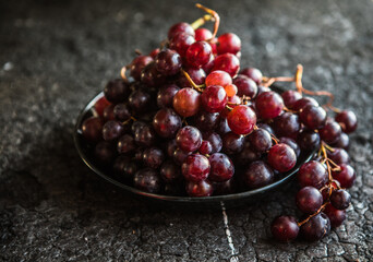 Bunches of red grapes on old black  wooden table . Symbol of autumn cornucopia, top view