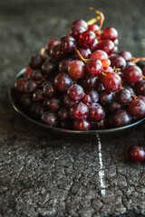 Bunches of red grapes on old black  wooden table . Symbol of autumn cornucopia, top view