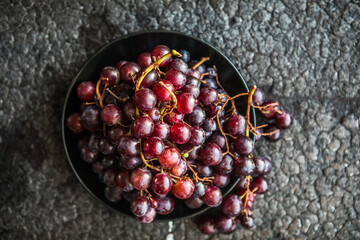 Bunches of red grapes on old black  wooden table . Symbol of autumn cornucopia, top view