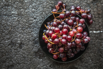 Bunches of red grapes on old black  wooden table . Symbol of autumn cornucopia, top view
