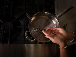woman adding mustard to pan 