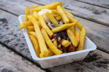 Portion of french fried potato chips with curry and mayonnaise sauce and onion