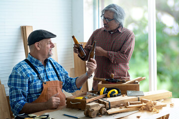 Interracial carpenter celebrating finishes his work by drinking beer in wood workshop