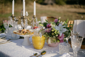 Table with fresh orange juice in a jug, breakfast in the garden.