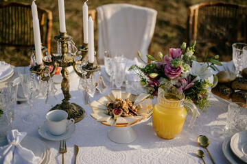 A table with fresh orange juice in a jug. Cheese with nuts and dried fruits, breakfast in the garden.