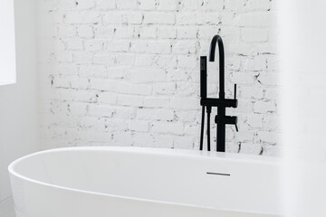 Part of white bath with black faucet