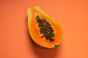 Papaya fruit on a orange background. Half papaya.