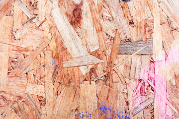 Particleboard chipboard texture with pink and blue spray paint, waste-wood product, wood chips, sawmill shavings, sawdust