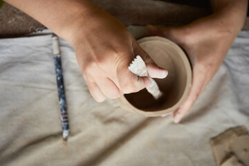 Female ceramist working in pottery studio. Ceramist's Hands Dirty Of Clay. Process of creating pottery. Master ceramist works in her studio