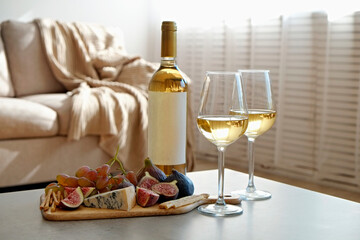 Bottle of a vintage chardonnay with two poured glasses, figs, grapes, blue cheese and grissini breadsticks. Copy space, top view, flat lay, close up, background.