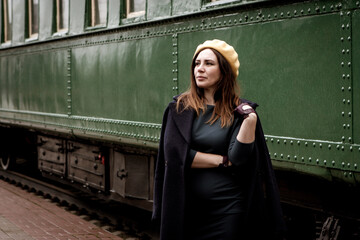 Woman in retro styled clothes standing by green vintage train