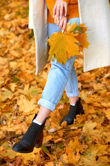 woman legs in jeans and boots walk in fallen leaves. copy space. shallow depth of field