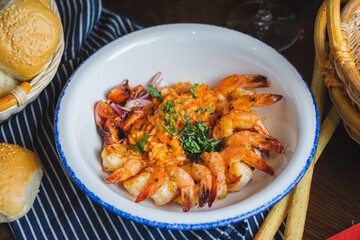 Traditional bright shrimp risotto in a bowl on a table in a restaurant with a beautiful decor in a dark key close-up.