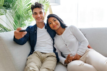 Obraz premium european couple in living room having fun on the sofa listing tv