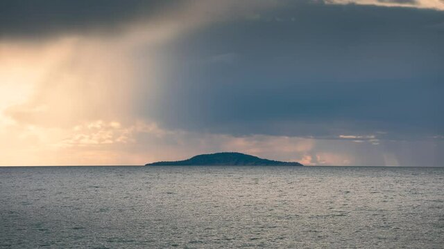 Time lapse of dramatic rain cloud over isalnd in the ocean on Oeland, rain falling down, orange sky, Sweden
