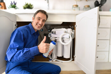 Technician installing reverse osmosis equipment under sink with ok sign
