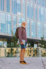 an adult gray-haired man with a beard goes to the office to work. a senior businessman in a shirt and with a laptop is making a career in a large company. a stylish European talks on the phone with