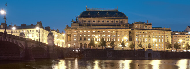 Beautiful Prague at night. Illuminated National Theater with reflection in Vltava river.