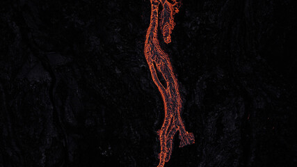 hot lava running on solidified black lava during night