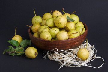 Wild pears in a ceramic vase on a black background. Pear branch. Pears on straw. Fruit harvest