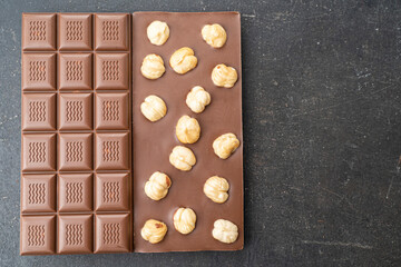 Milk chocolate with hazelnuts on black background. Handmade organic chocolate with nuts for candy store