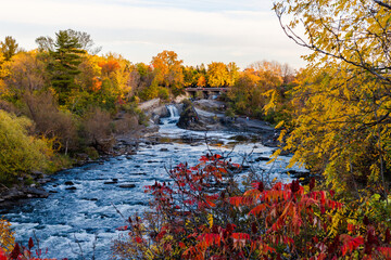 The Hog's Back Falls and Bridge, Prince of Wales Falls waterfalls on the Rideau River in Ottawa city of Canada in autumn. Colorful nature in park with river - obrazy, fototapety, plakaty