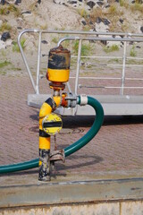 tank system in the port with a hose as a supply line to a ship in front of a metal gangway