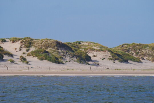 blue waves of the german north sea with the beach and sand dunes overgrown with grasses of the north sea island norderney
