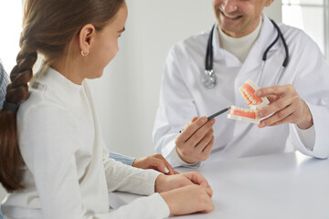 Close up of male dentist consult little girl child patient in private hospital or clinic. Smiling doctor talk with kid about oral care and hygiene for healthy teeth. Medicine, dentistry concept.