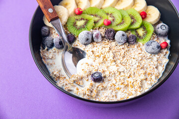 oatmeal bowl fruit banana, kiwi, berries, blueberries ready to eat meal snack on the table copy space food background rustic. top view keto or paleo diet