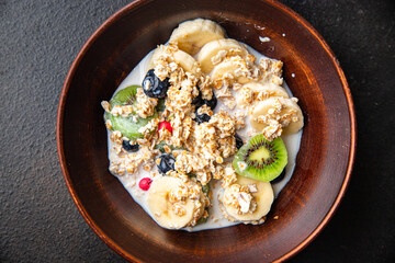 oatmeal bowl fruit banana, kiwi, berries, blueberries ready to eat meal snack on the table copy space food background rustic. top view keto or paleo diet