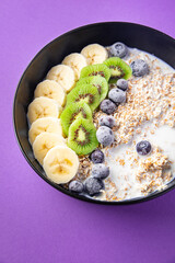 oatmeal bowl fruit banana, kiwi, berries, blueberries ready to eat meal snack on the table copy space food background rustic. top view keto or paleo diet