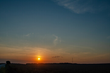 Fototapeta na wymiar Sunset over the field. The road goes beyond the horizon