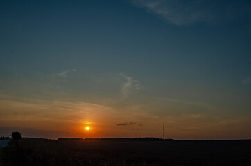 Sunset over the field. The road goes beyond the horizon