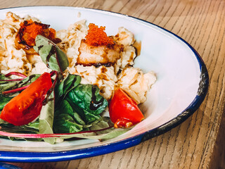 salad with shrimps, caviar and vegetables in a white plate on wooden table