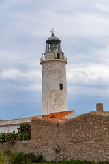 Fototapeta na wymiar Far de la Mola, a lighthouse on the southeastern tip of the island of Formentera in the Balearic Islands, Spain - White lighthouse on the top of a cliff in the Mediterranean Sea