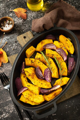 Pumpkins slice with rosemary and purple onion, baking fresh healthy food with spice on a dark stone background. Keto or paleo diet veggie vegan or vegetarian.
